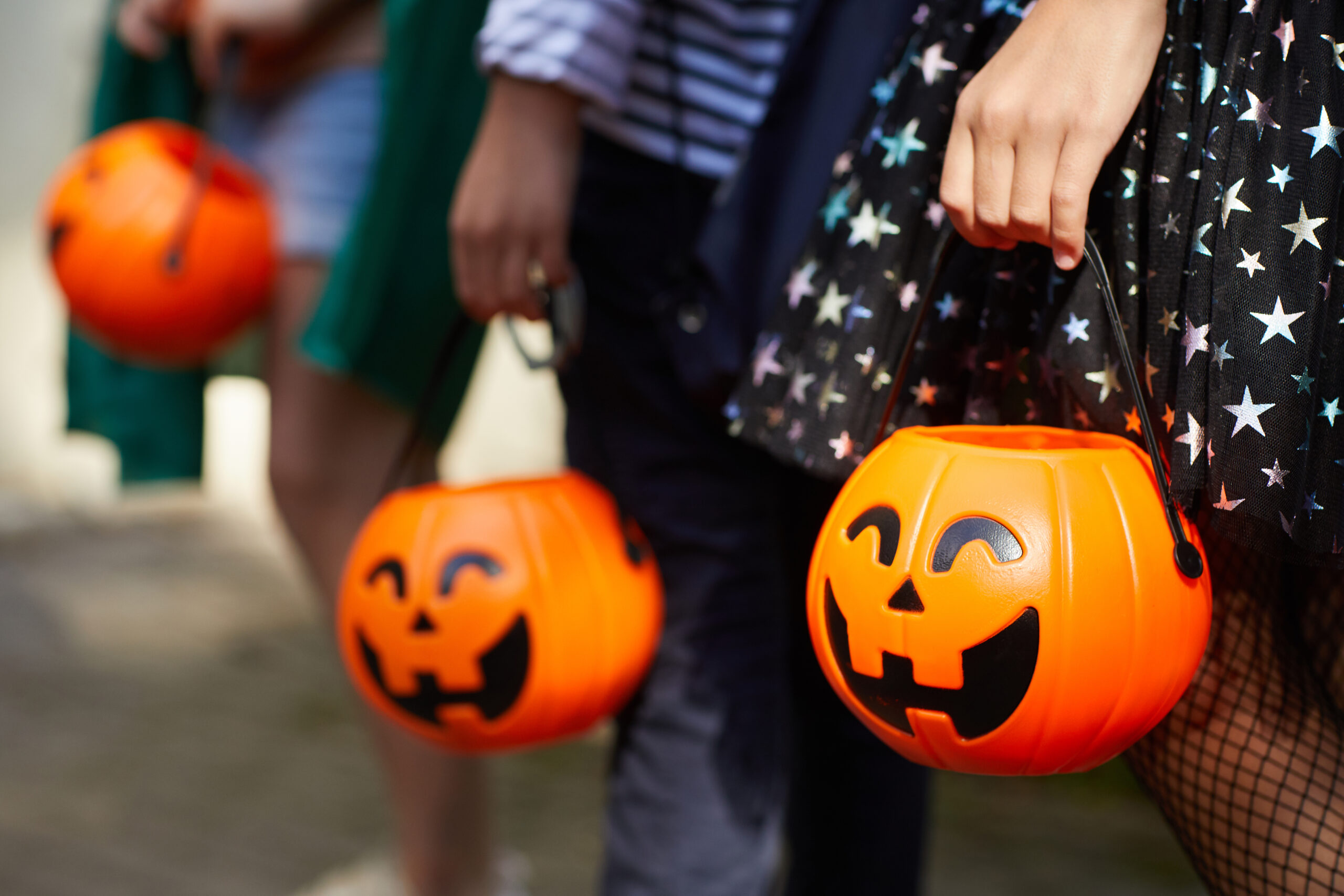 Close-up of children with pumpkins bags playing trick or treat outdoors for halloween safety tips blog