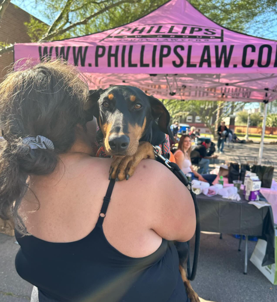 photo of small dog on owner's shoulder at feeding arizona event