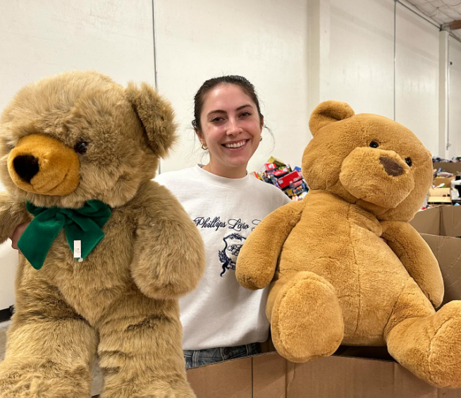 volunteer posing with two stuffed toy teddies