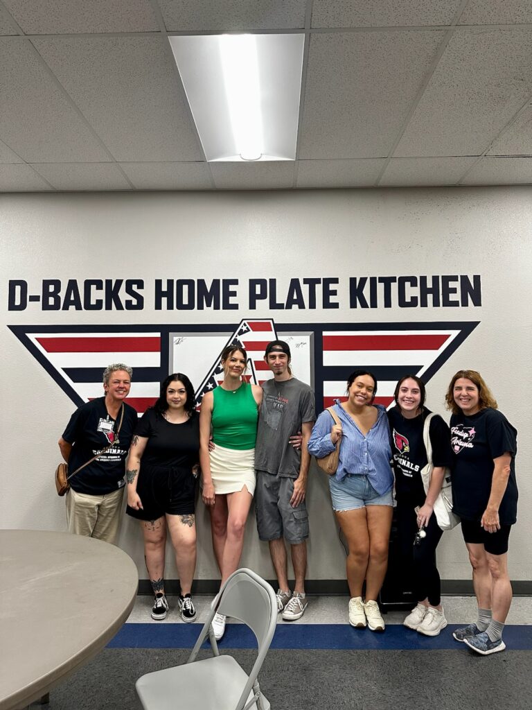 volunteers and others pose at mana house mural