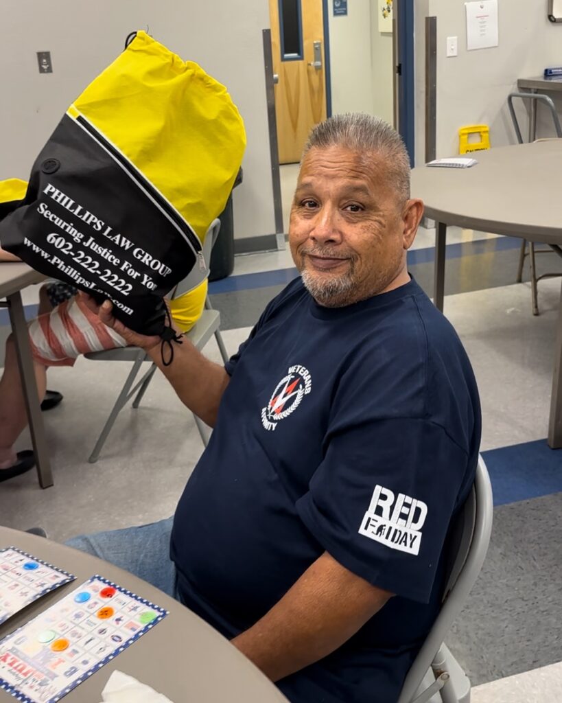 veteran at mana house holding up phillips law group canvas bag