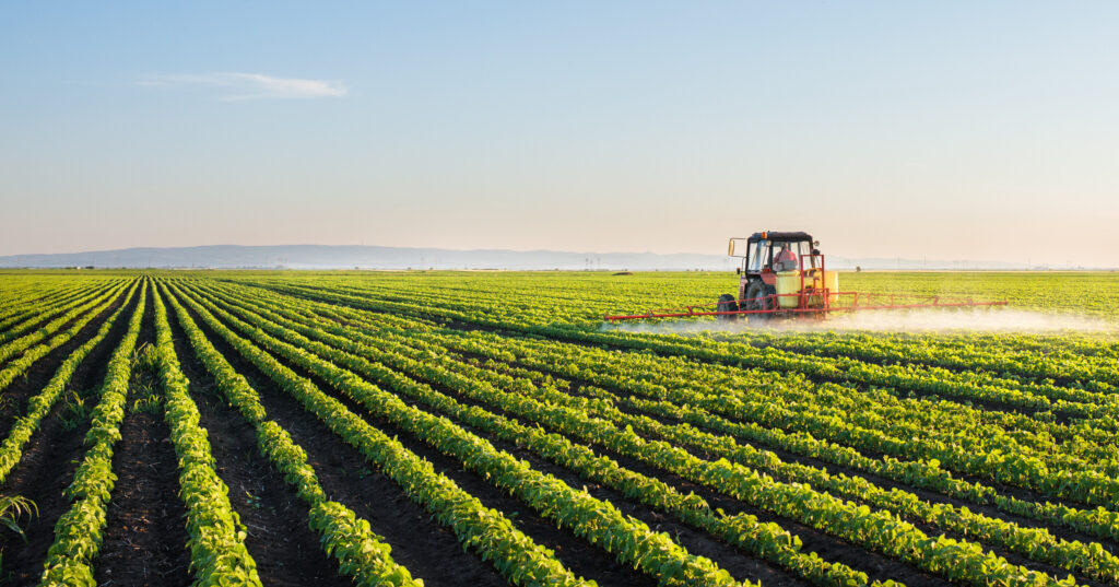 Tractor spraying soybean field for dacthal pesticide blog post