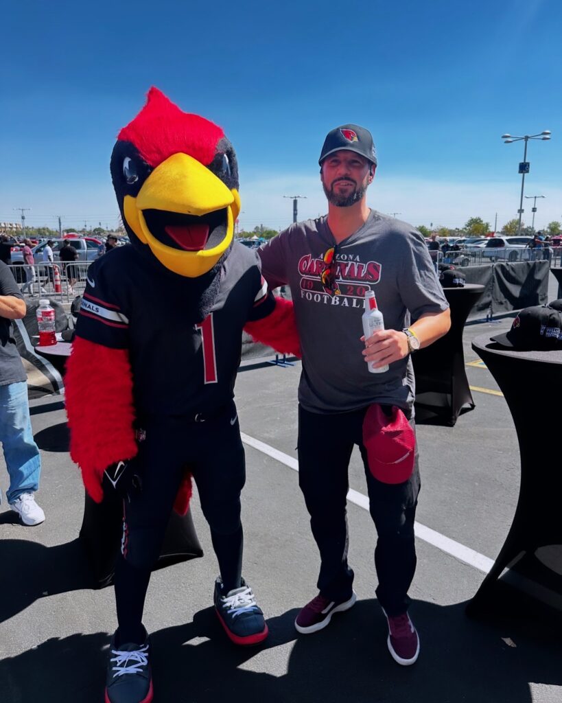 person posing with big red mascot at arizona cardinals game