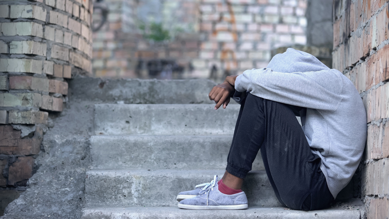 Lonely male teen sitting building stairs