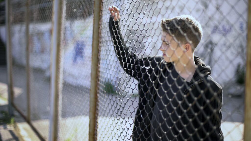 image of young man holding onto a fence for illinois juvenile detention facilities blog post