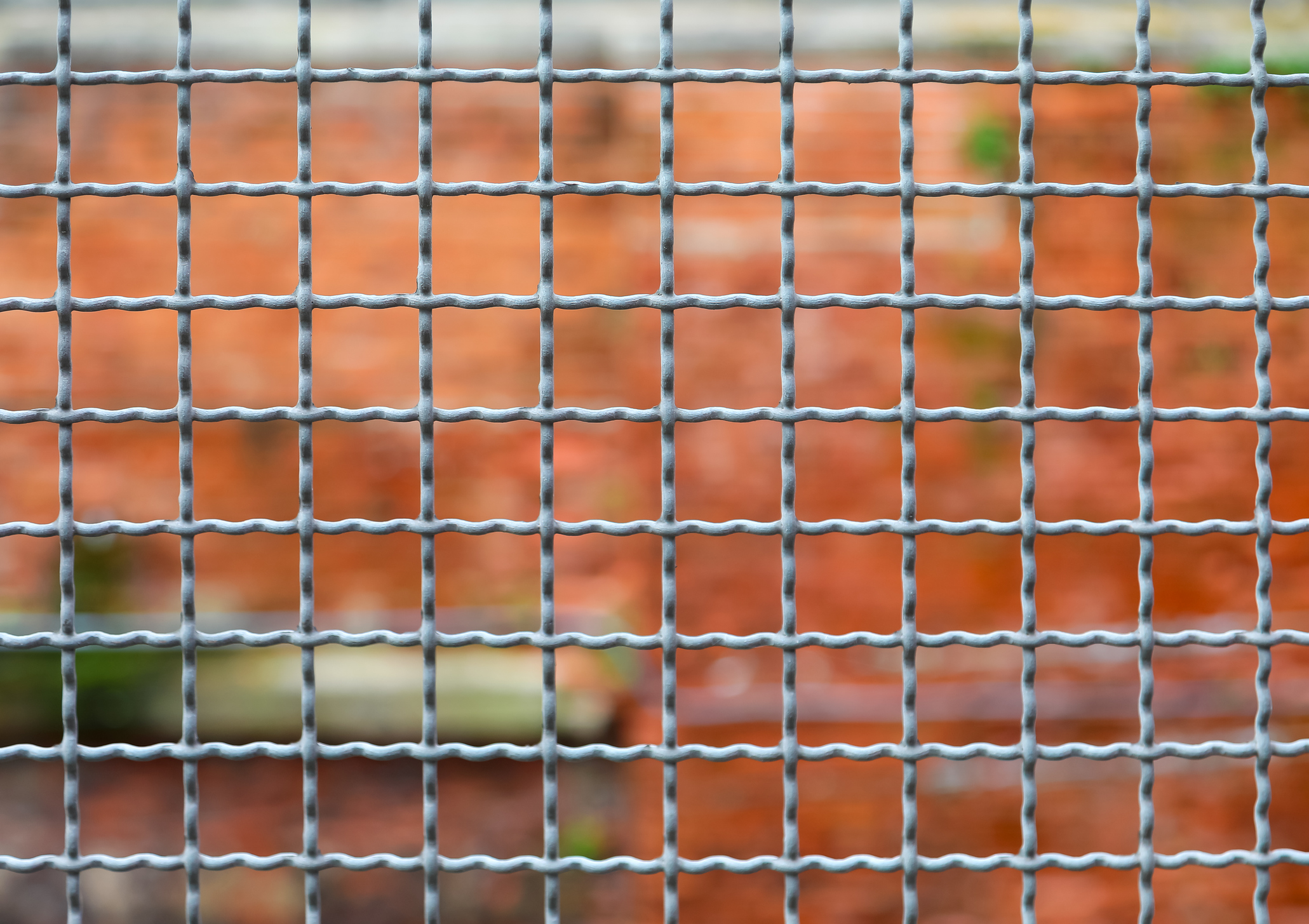 border separation fence and the brick wall of the penitentiary out of focus in background