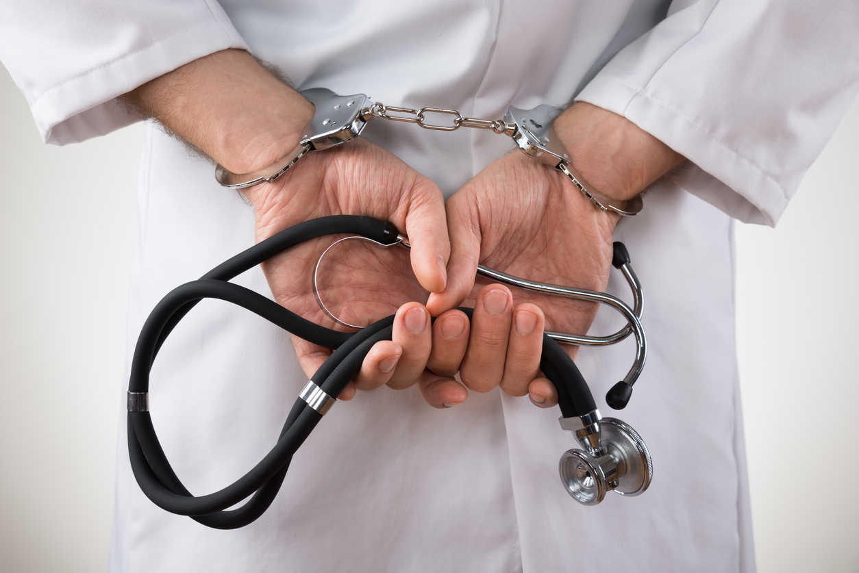 Close-up Of Doctor Hands With Stethoscope In Handcuffs