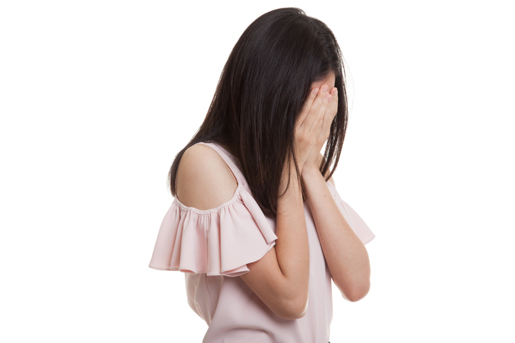 Sad young Asian businesswoman cry with palm to face.
