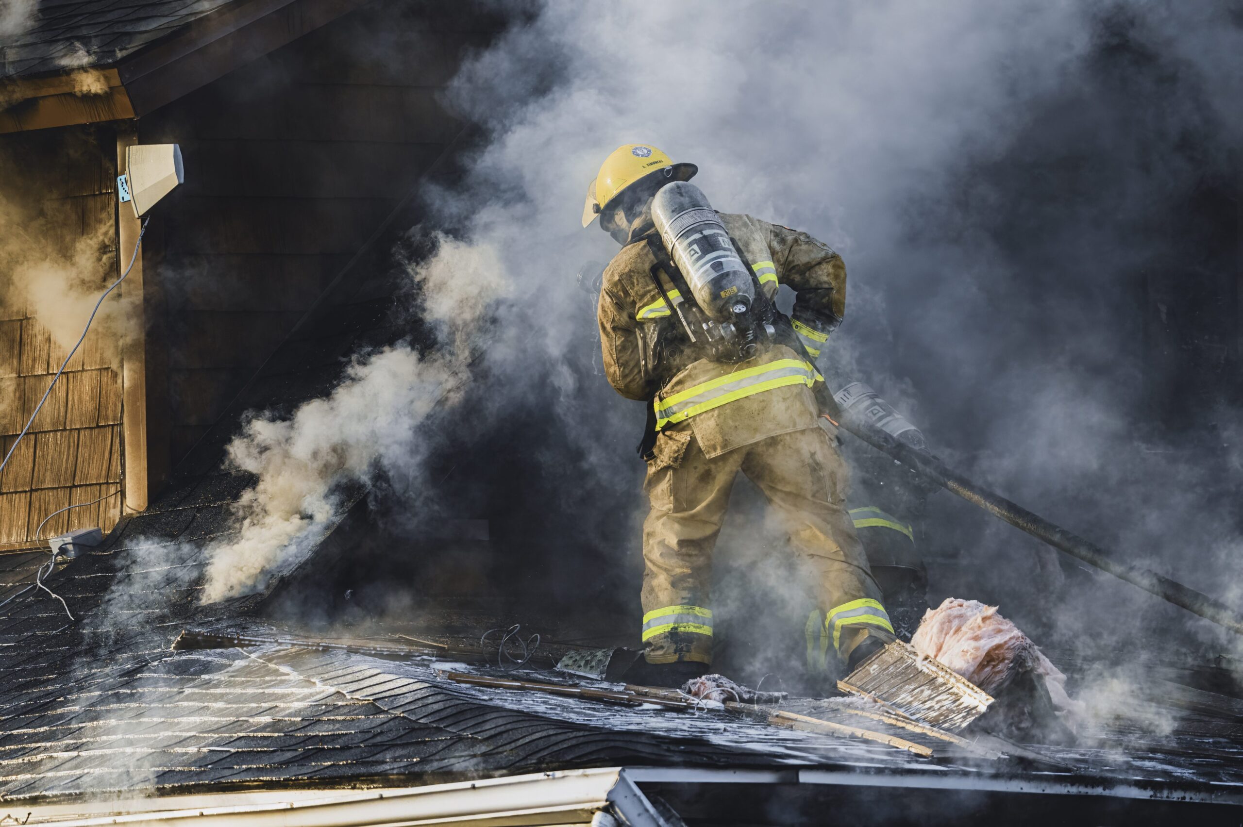 image of firefighter fighting a fire in a haze of smoke for Firefighter PFAS Injury Compensation Act blog post