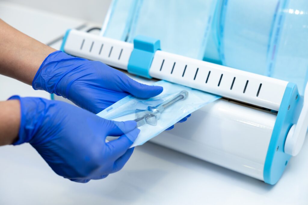 Unrecognizable doctor doing sterilization procedure hands in blue gloves holding dentist tools