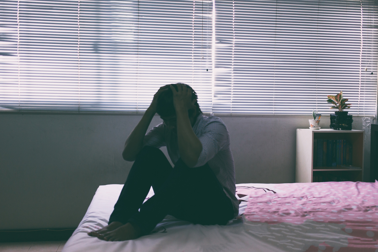 The man sitting on the bed in the bedroom, stress