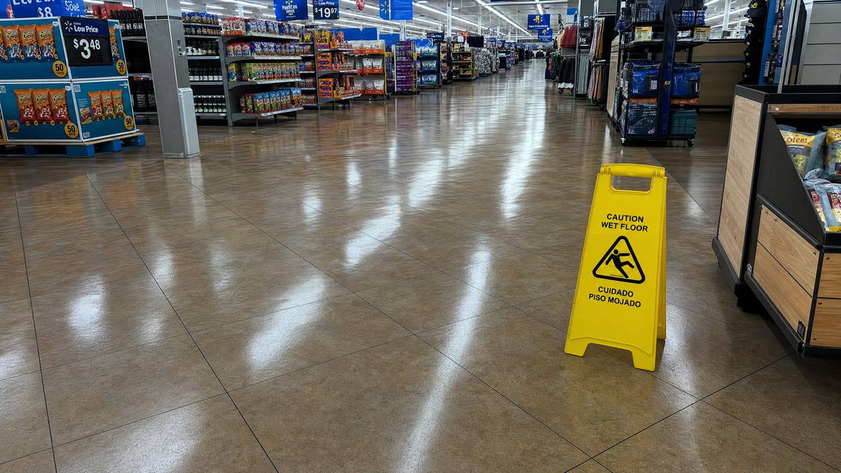 Wet floor warning sign on shiny tile floor in large retail store
