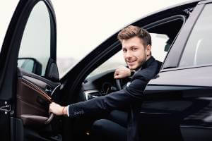 businessman smiling as he closing door of car