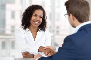 woman smiling shaking hands in meeting with businessperson